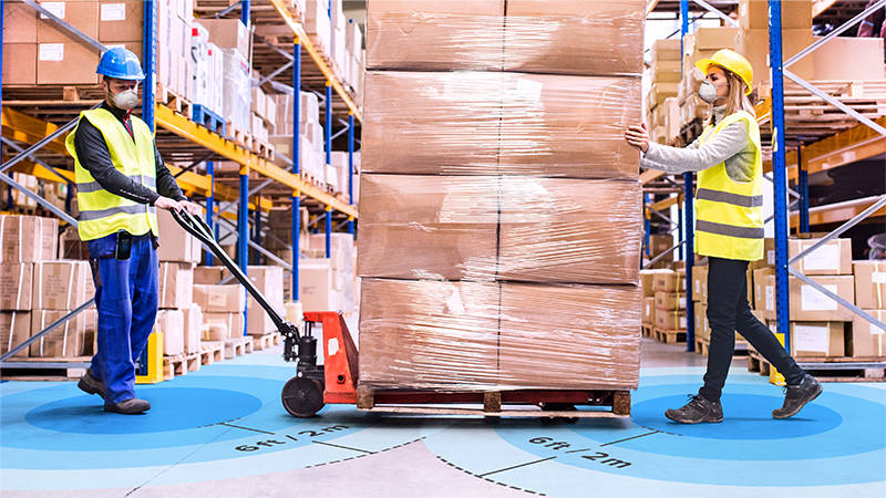 Warehouse inventory, with two workers moving a hand truck
